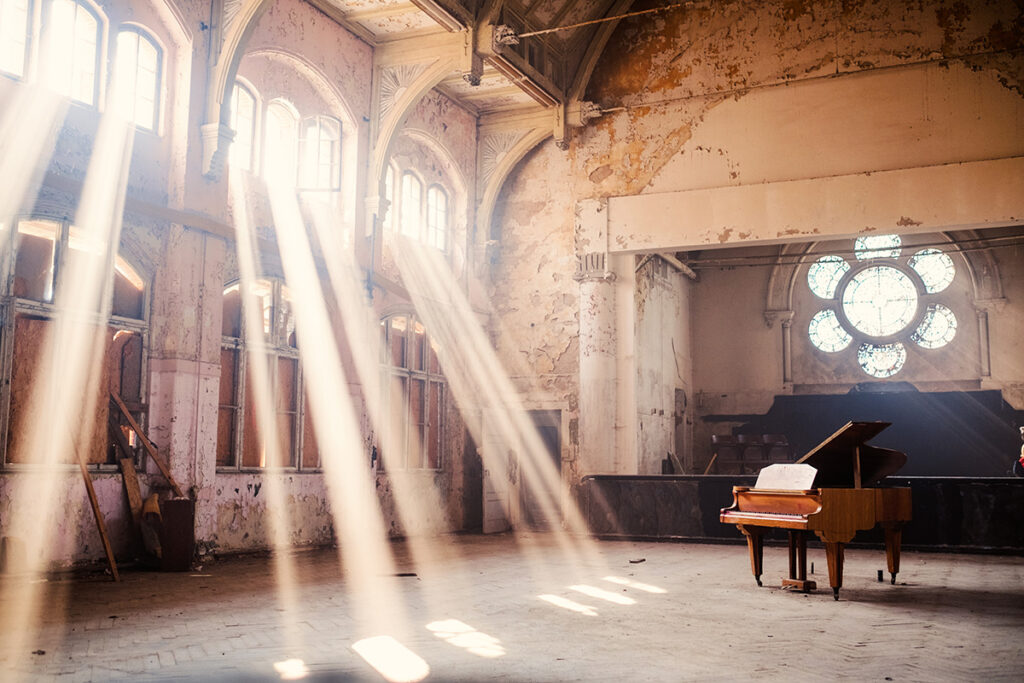 Verlassener Innenraum mit einem alten Klavier mit Lichteinfall durch die Fenster